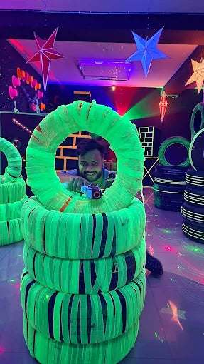 Person standing inside a large green inflatable tube in a laser tag game room with colorful decorations.
